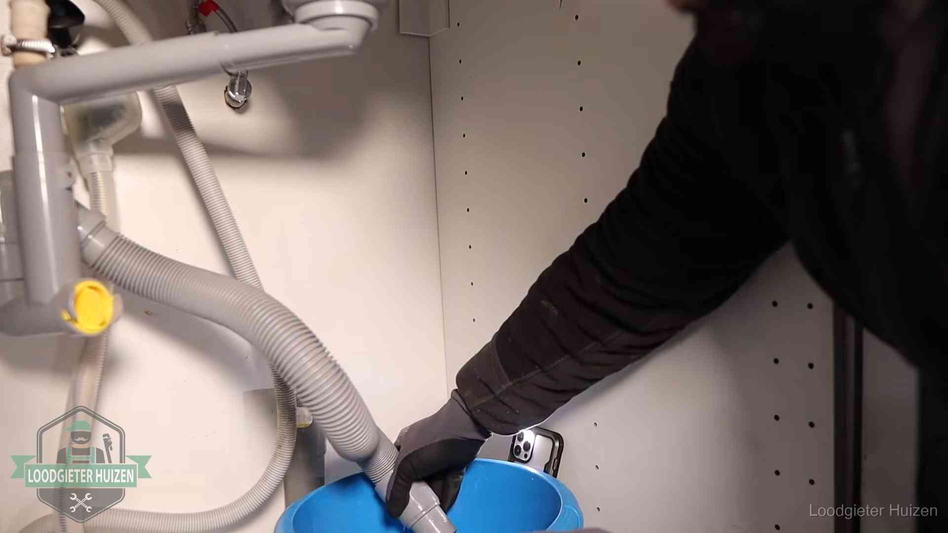 Afvoerslang loopt leeg in een emmer onder de gootsteen in Huizen, een klus die je zelf kunt doen