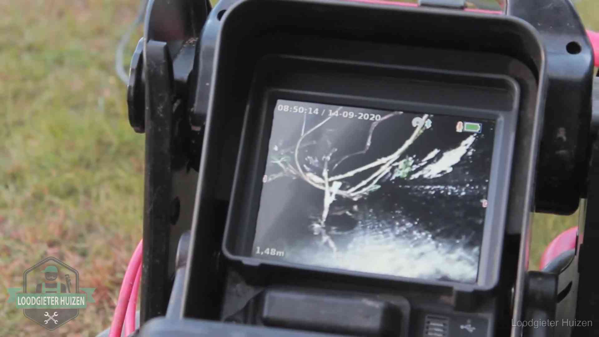 Monitor van een rioolcamera toont wortelingroei in de rioolbuis bij een woning in Huizen