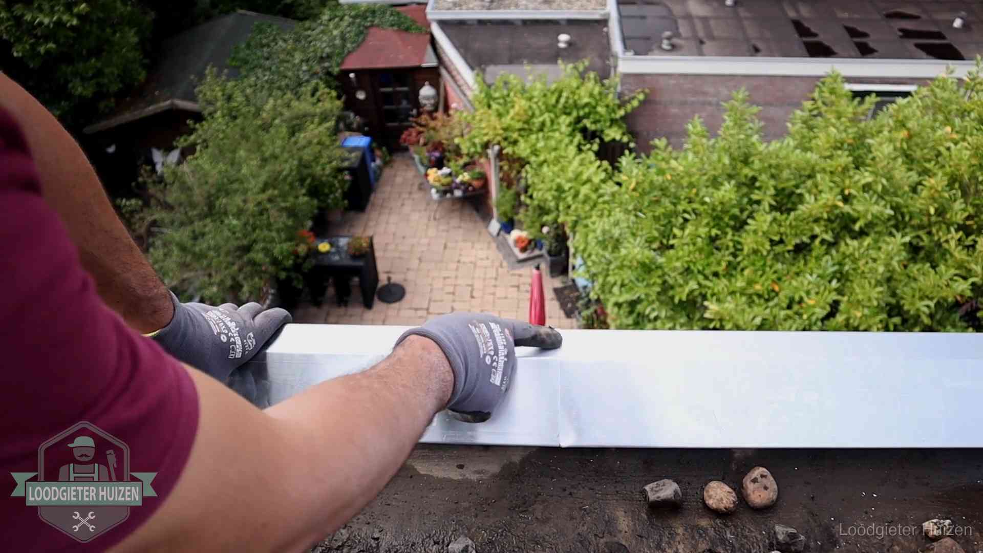 Daklekkage geregeld in Huizen Vakman plaatst een daktrim op de dakrand van een woning in Huizen