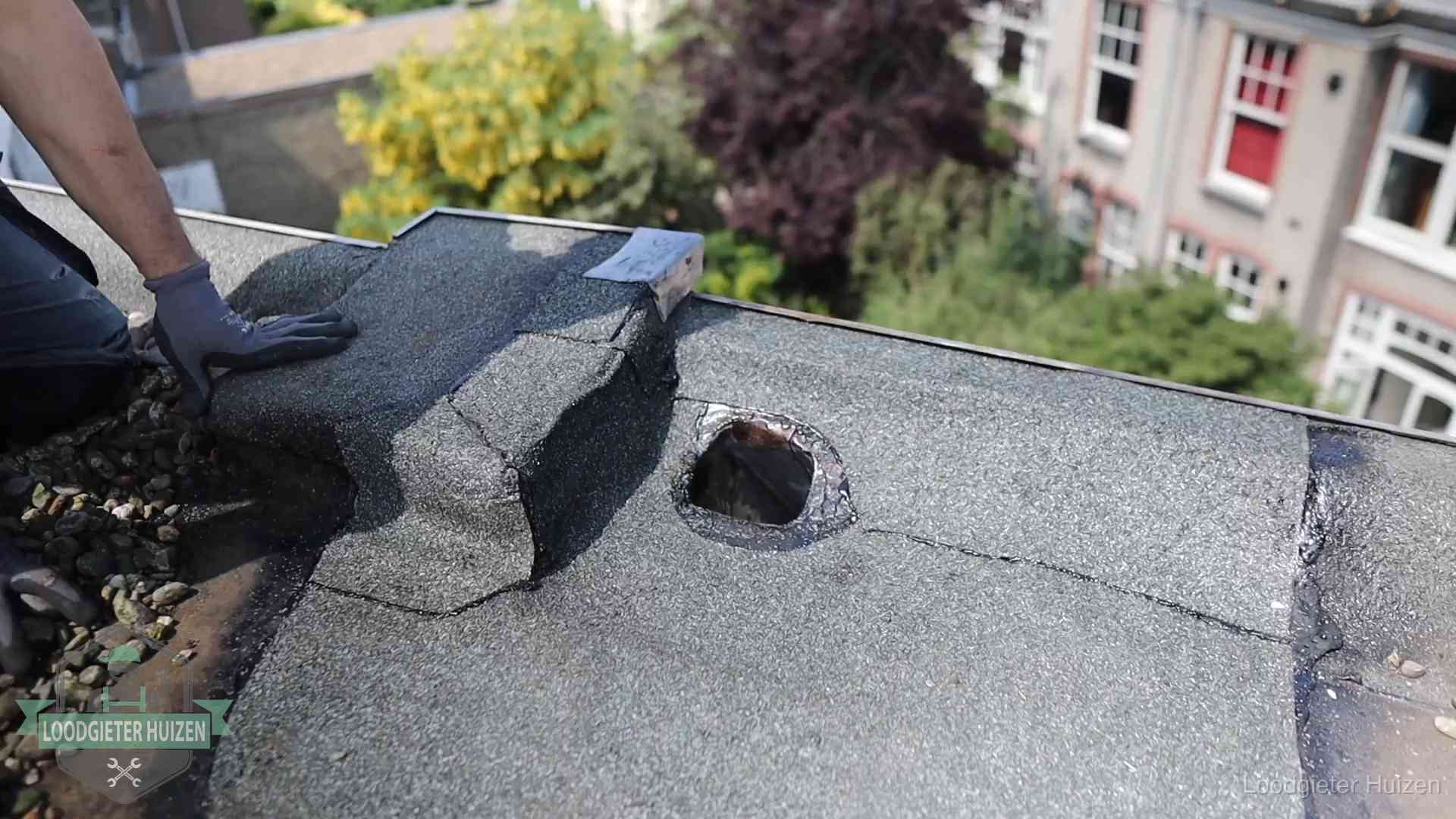 Daklekkage-inspectie op een plat dak in Huizen Loodgieter inspecteert een beschadigd bitumen plat dak tijdens een daklekkage-inspectie in Huizen