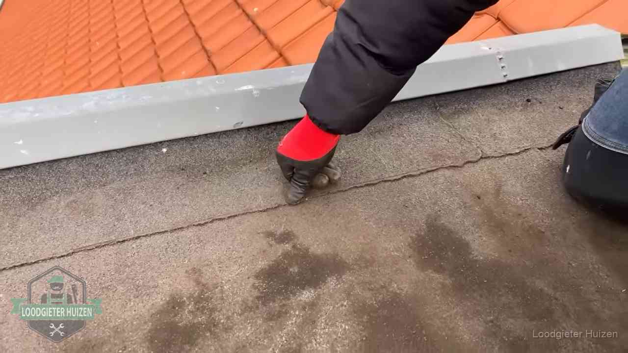 Lekkage bij de naad van een plat dak in Huizen Vakman wijst een naad met vochtplekken aan op een bitumen plat dak in Huizen