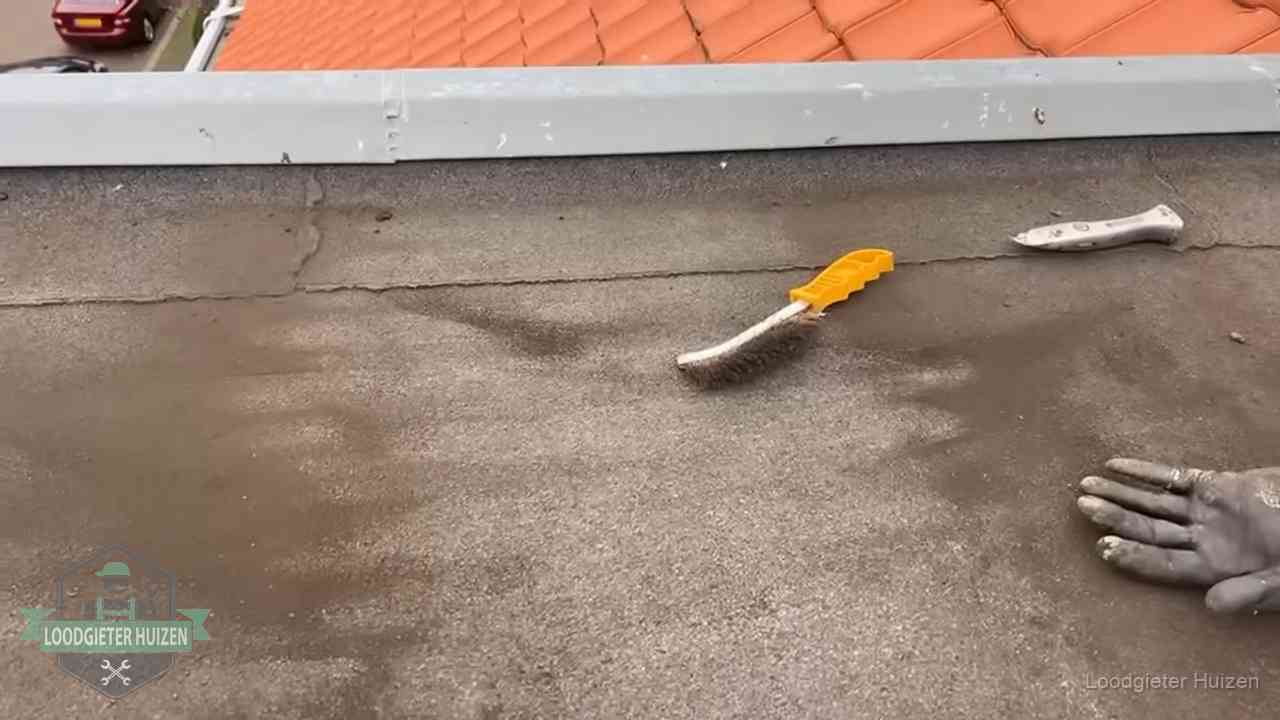 Kosten van daklekkage-reparatie in Huizen Dakdekker bereidt een bitumen plat dak voor op reparatie bij de daktrim in Huizen