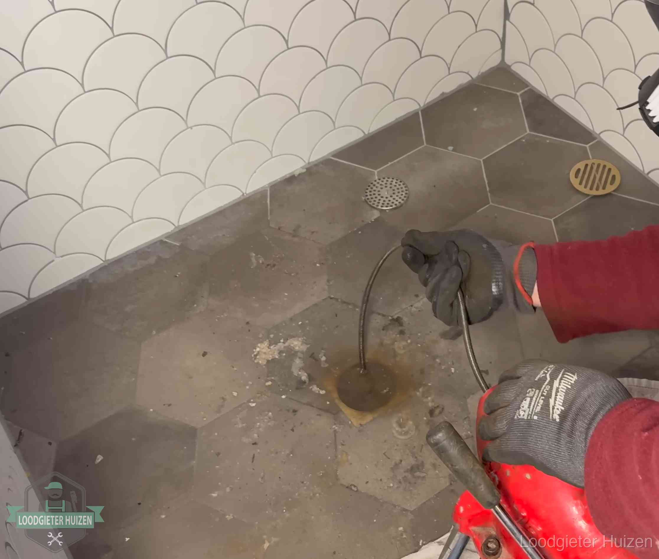 Ontstoppingsveer gaat in een geopend doucheputje in Huizen waar het water omhoogkwam