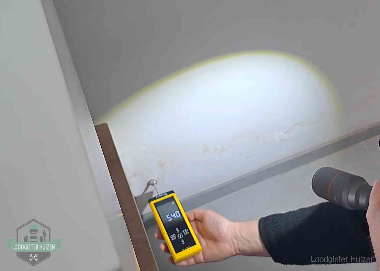 Lekdetectie-technieken in Huizen Vochtmeter tegen een natte wand met lekkagesporen in Huizen