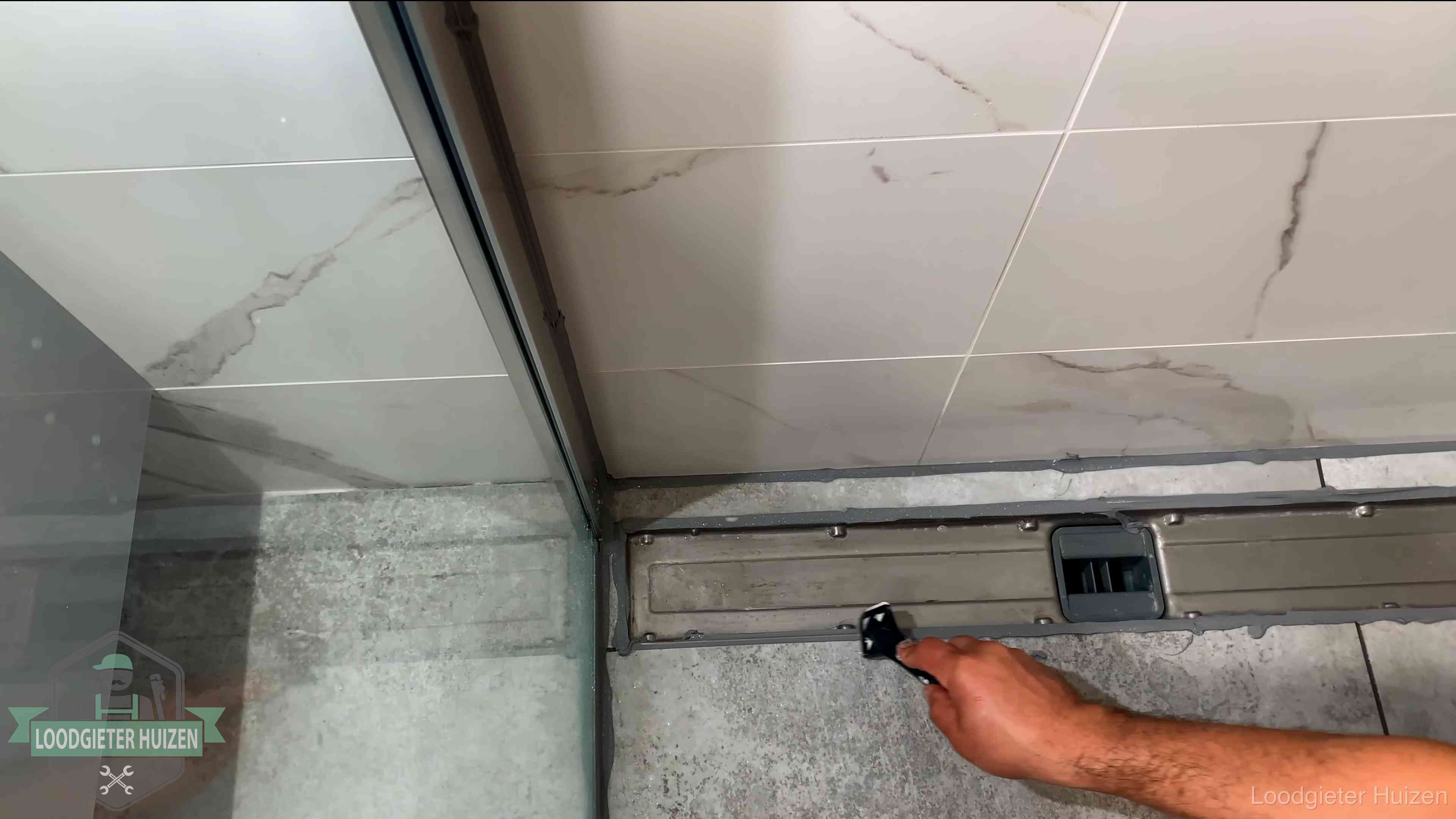 Lekkage in de badkamer verhelpen in Huizen Verse kitrand langs de douchegoot in een betegelde badkamer in Huizen