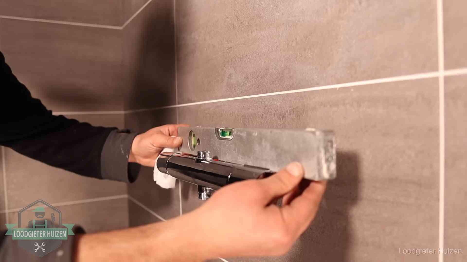 Loodgietersbedrijf voor sanitair in Huizen Loodgieter lijnt een douchekraan uit met een waterpas in een woning in Huizen