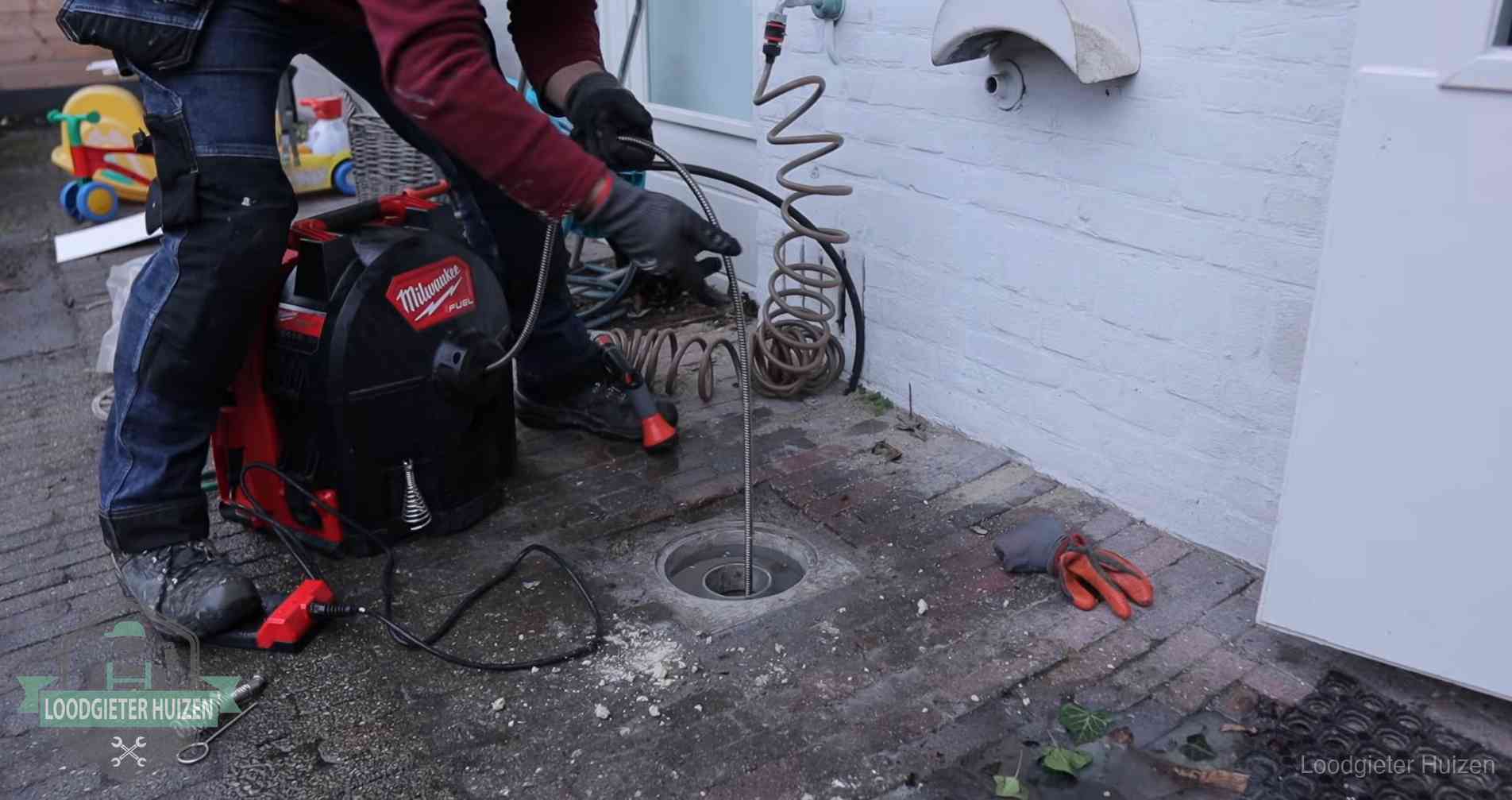 Ontstoppingsputje in de bestrating naast de gevel van een woning in Huizen