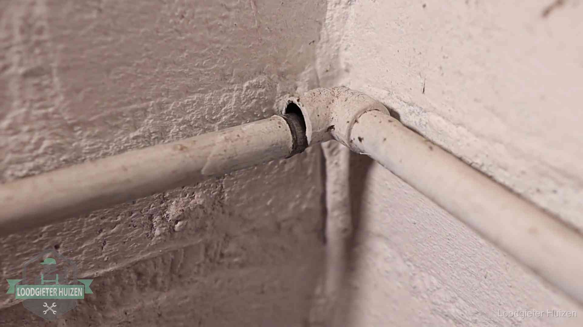 Oude waterleidingen en verborgen lekkage in Huizen Oude geverfde waterleiding met een losliggende fitting in een woning in Huizen