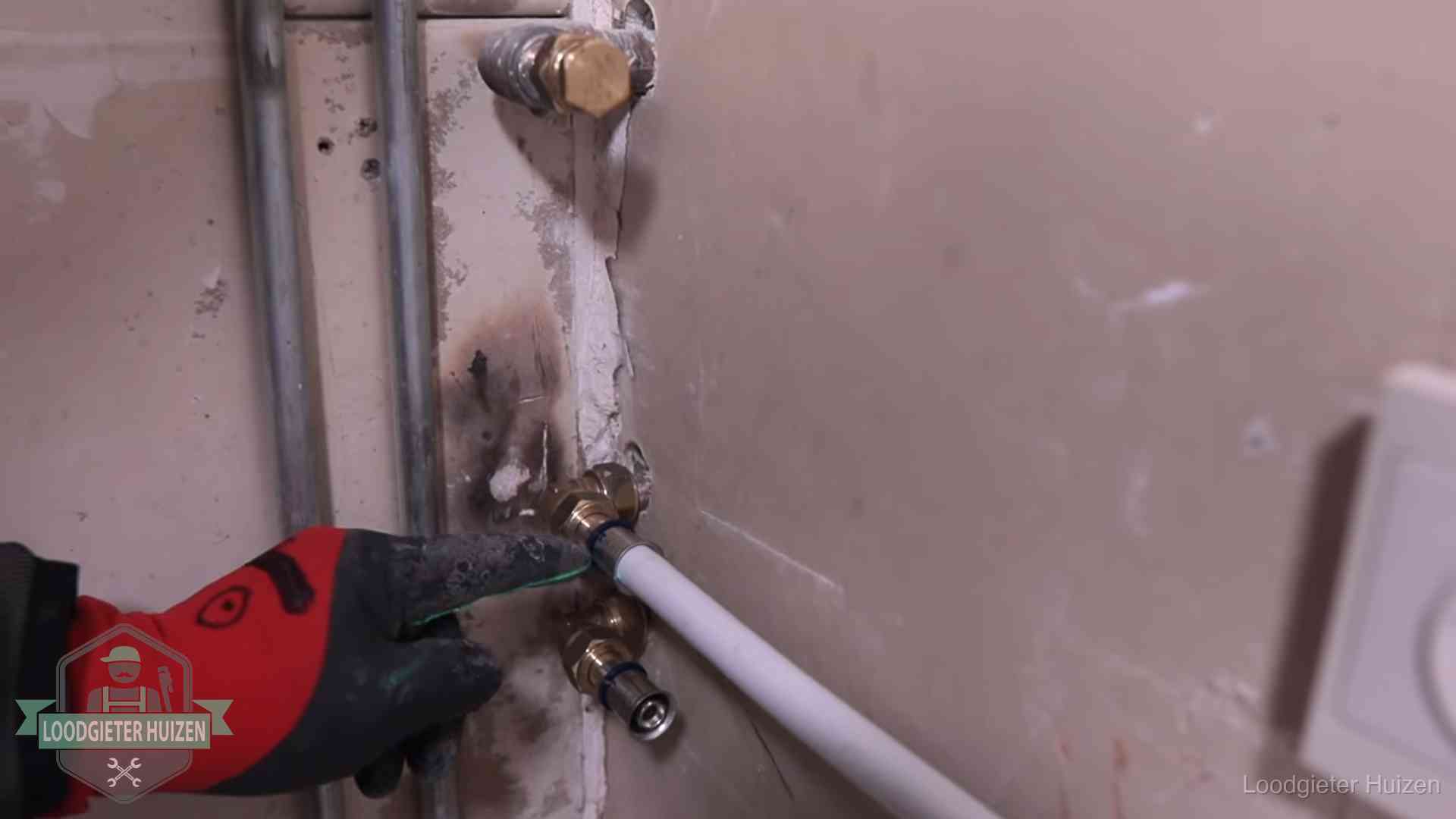 Garantie op loodgieterswerk in Huizen Loodgieter wijst de persfitting op nieuwe muuraansluitingen aan in een woning in Huizen