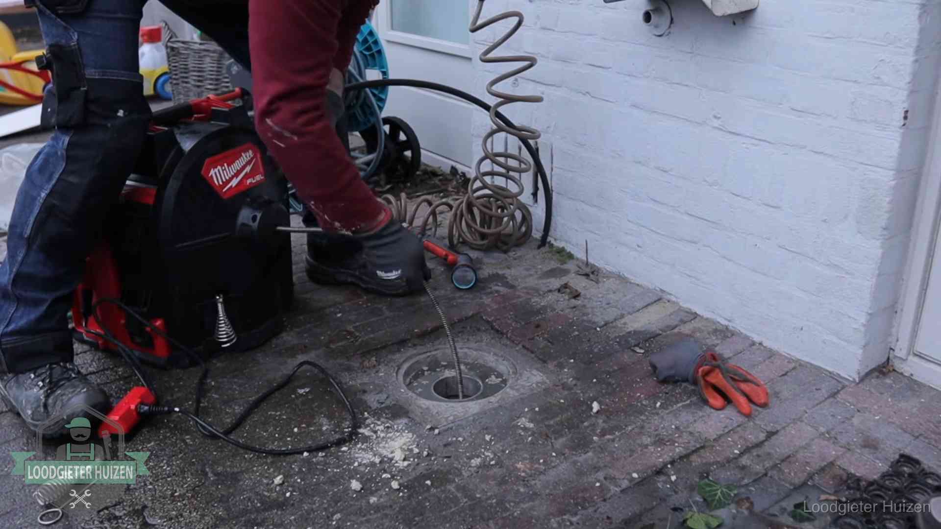 Spiraalmachine bij een ontstoppingsputje in de bestrating in Huizen