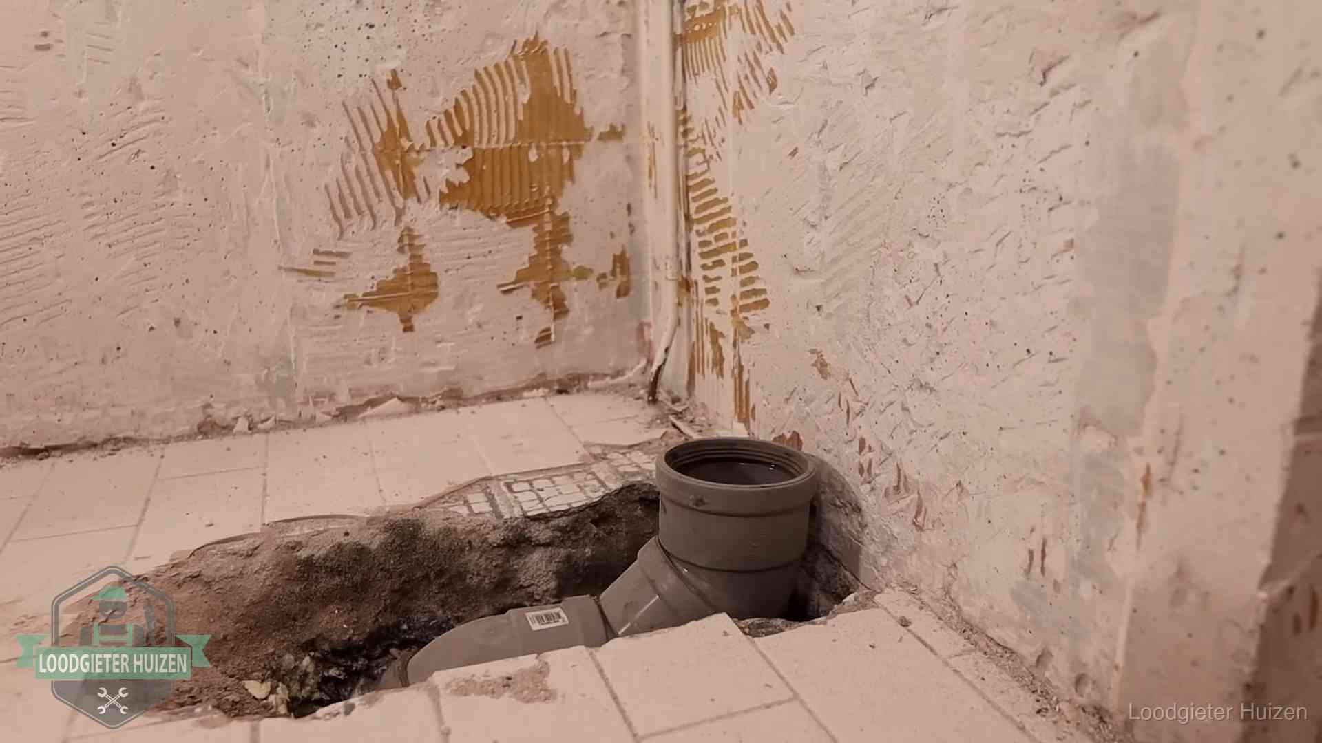 Opengebroken vloer met een nieuwe pvc-rioolbocht in een gegraven sleuf in Huizen