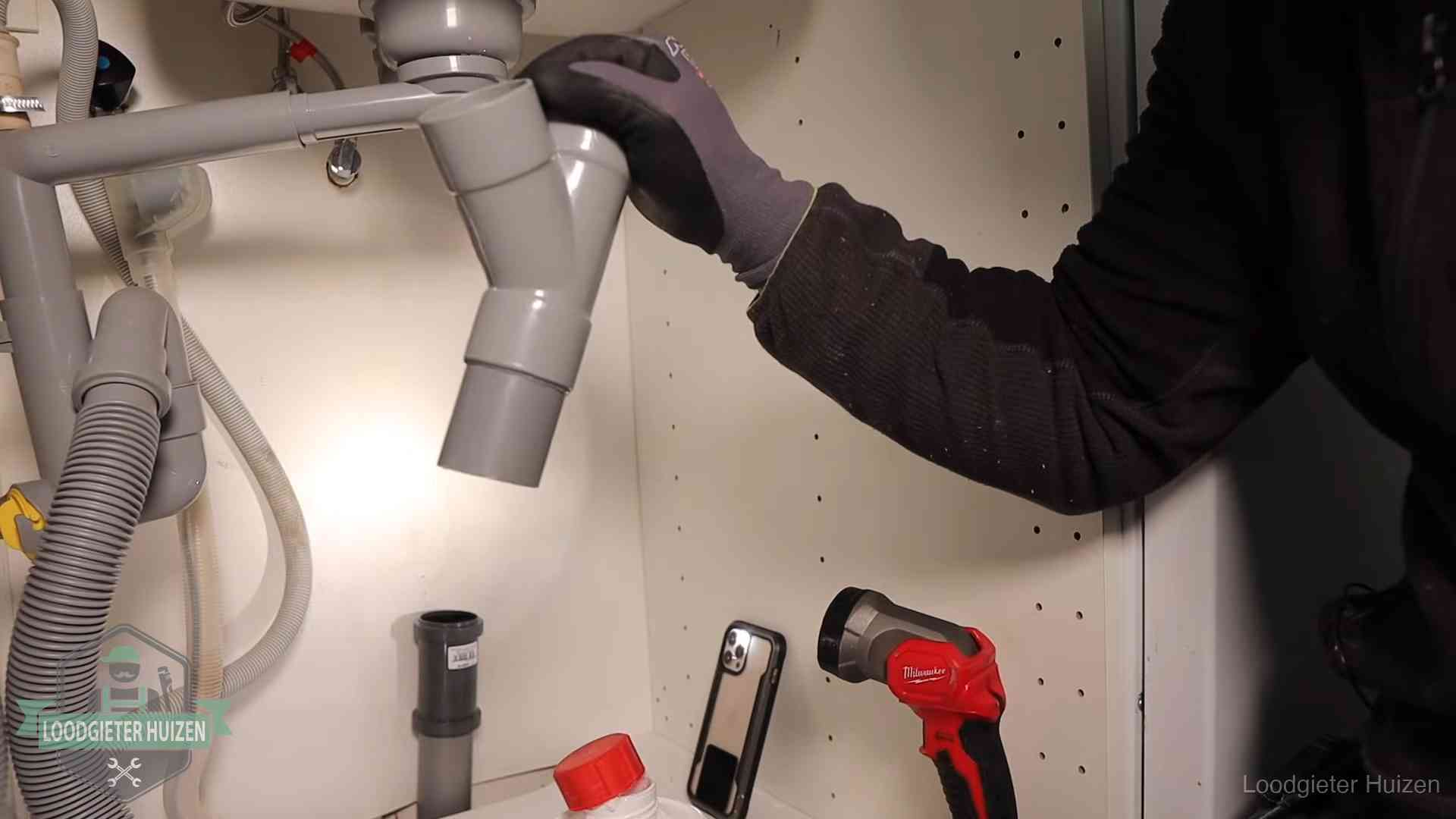 Loodgieter demonteert het sifon- en afvoerwerk onder een gootsteen in Huizen bij stankklachten