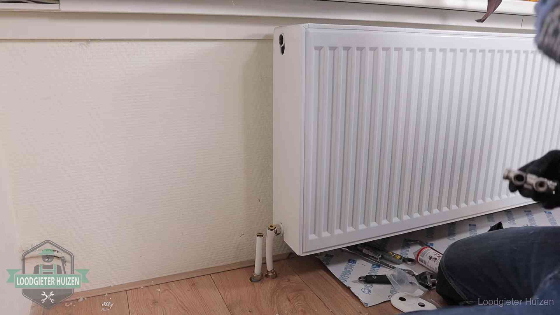 Verwarming per wijk in Huizen Nieuw gemonteerde radiator in een woonkamer in Huizen