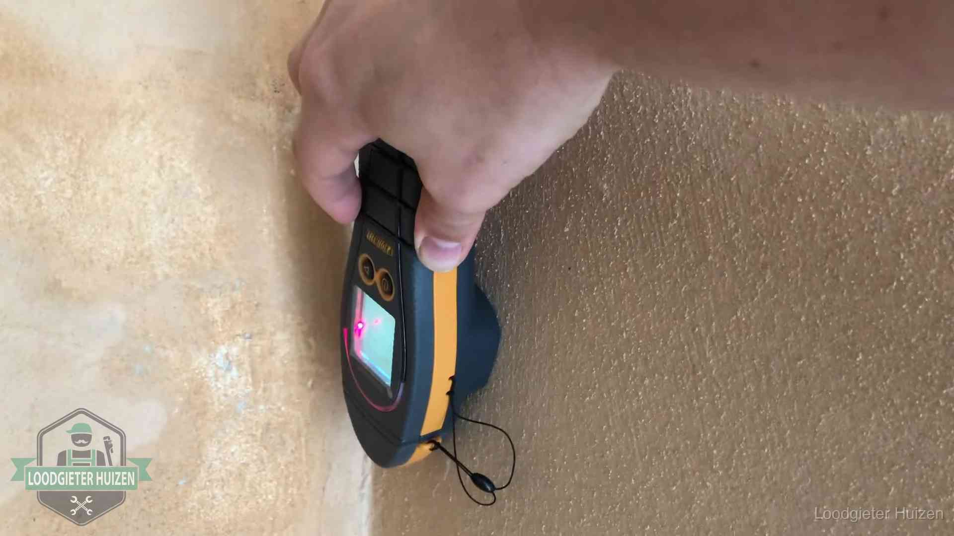 Daklekkage opsporen zonder hakwerk in Huizen Vochtmeter tegen een muur met vochtplekken tijdens het opsporen van een daklekkage in Huizen