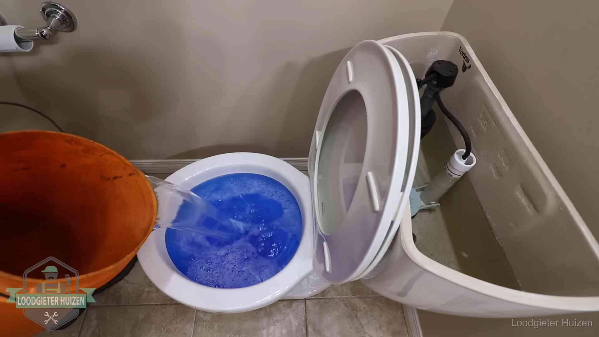 Water komt omhoog in de wc in Huizen Water bij de wc-pot wordt met een emmer weggewerkt om schade te beperken in Huizen
